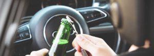 Image showing a person opening a beer while driving